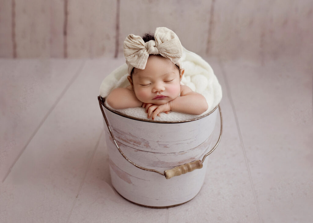 Newborn safely posed in bucket by Kelsie Kelly Photographer in Edmonton