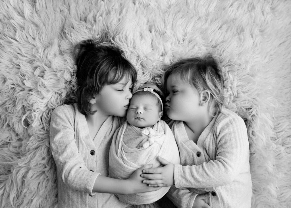 Sisters snuggling newborn baby sister |Photo by Kelsie Kelly Photographer | Edmonton studio newborn photography
